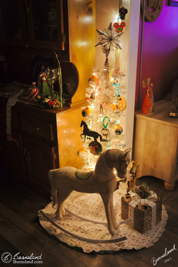 A rocking horse sits in front of a Christmas tree at our house, one of our Christmas 2023 decorations